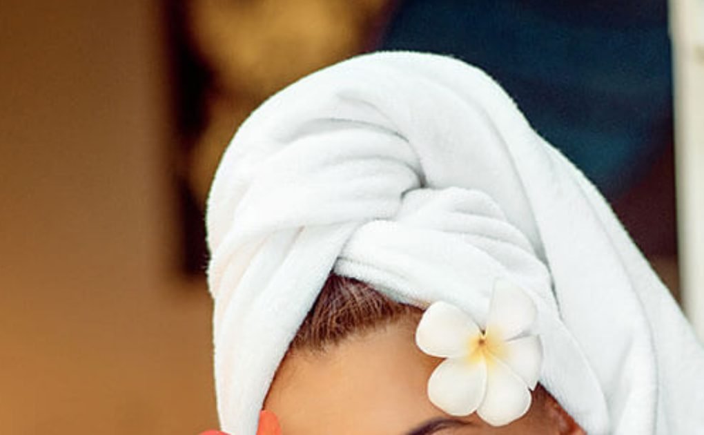 Spa guest relaxing in a towel with a plumeria flower